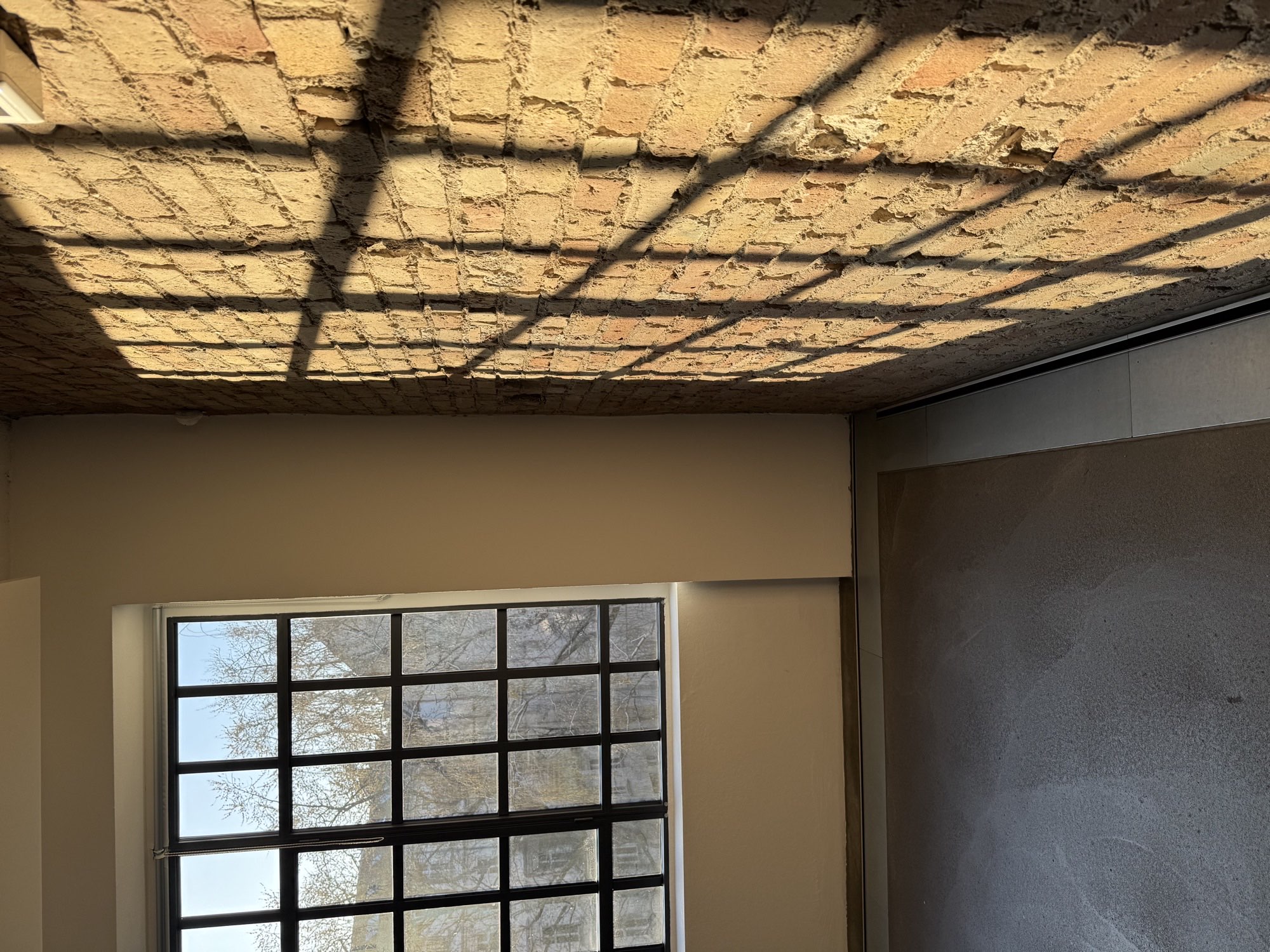 Backsteindecke mit Lichtspiel durch Sprossenfenster
